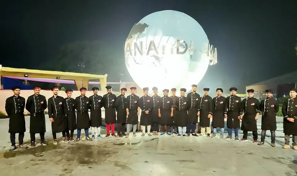 The service brigade lined up in uniform before an illuminated globe at a banquet venue.