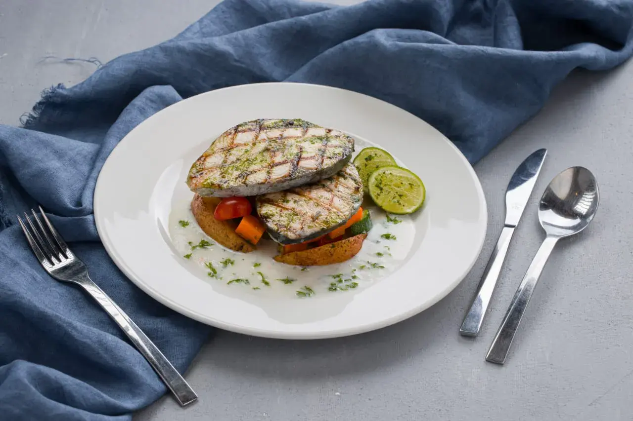 A plated fish course with seasonal vegetables.