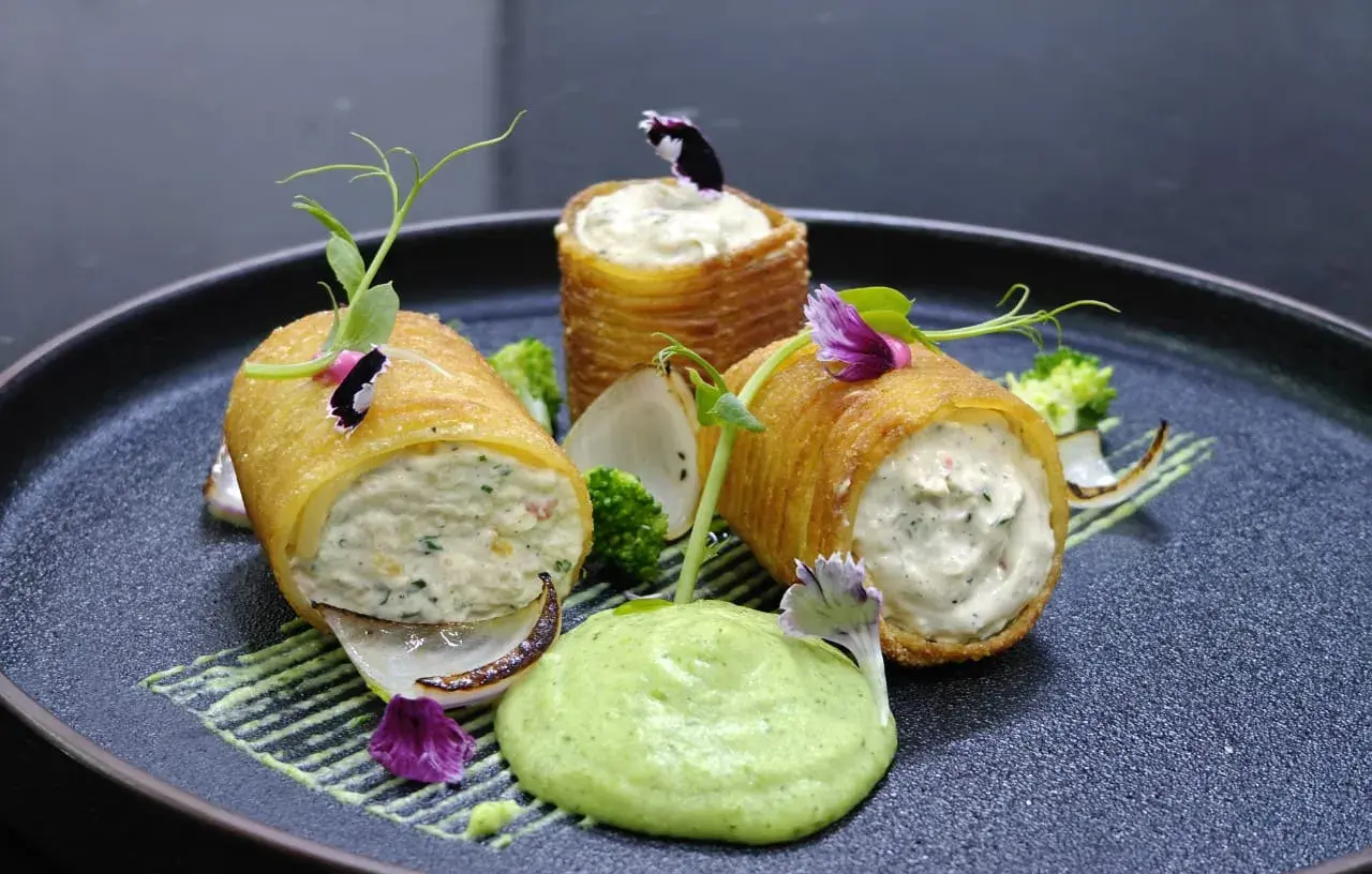 Filled pastry cylinders plated with a herb purée.