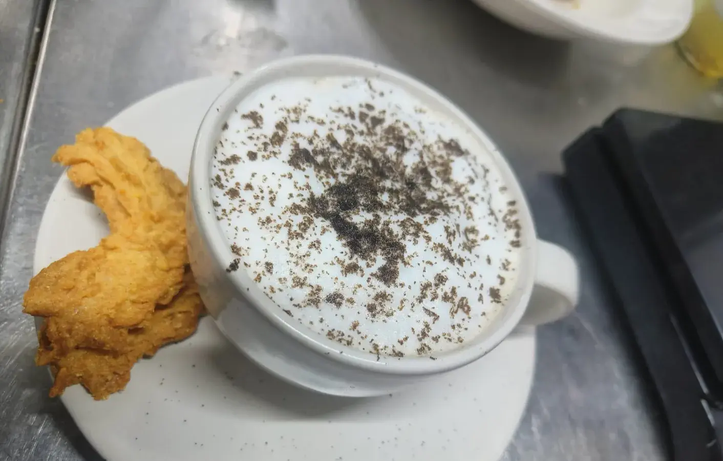 A cappuccino served alongside a fried side.