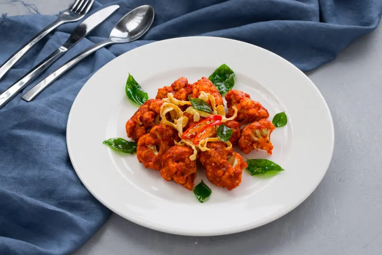 A prawn dish plated with basil.