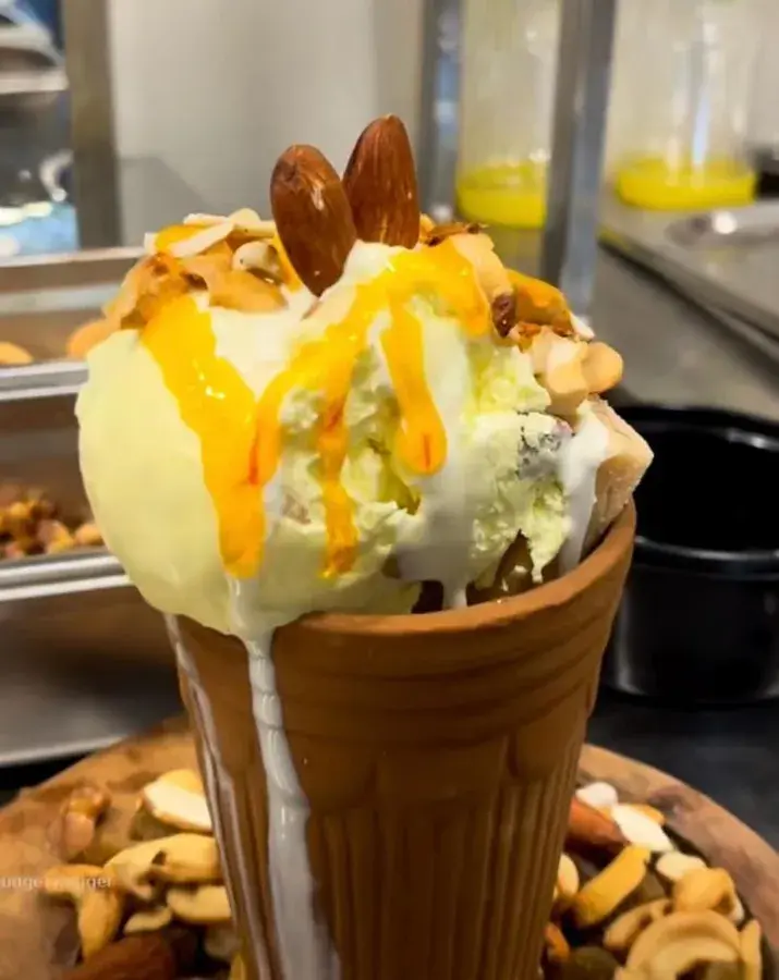 A dessert cone plated with nuts and sauce.