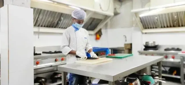 A chef at the preparation counter of a commercial kitchen.