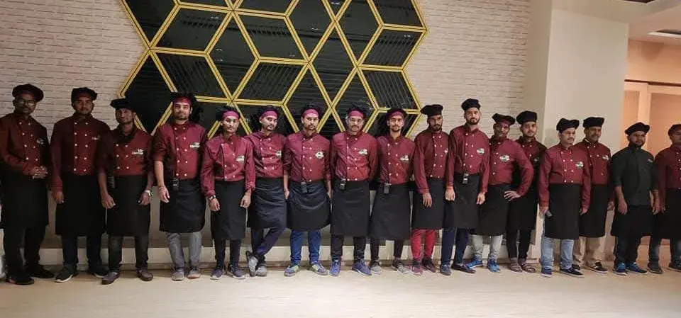 The team in maroon service uniform lined up inside the venue before guests arrive.