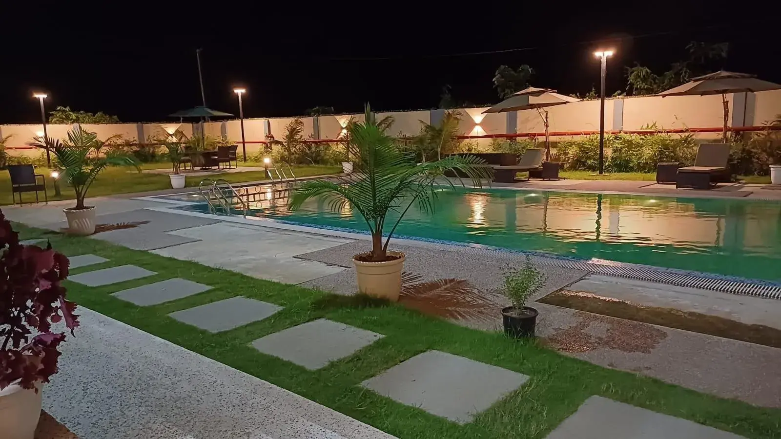 The pool and lawn of a resort project at night.